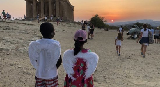 Tempio della Concordia al tramonto con due bambini che indossano le ali di icaro mentre ne guardano la statua di bronzo