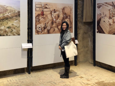 Laura Danile davanti a pannelli a colori che rappresentano la costruzione dei templi al Museo Archeologico